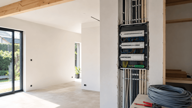 Coffret électrique ouvert avec câblage et conduits dans une habitation moderne en construction